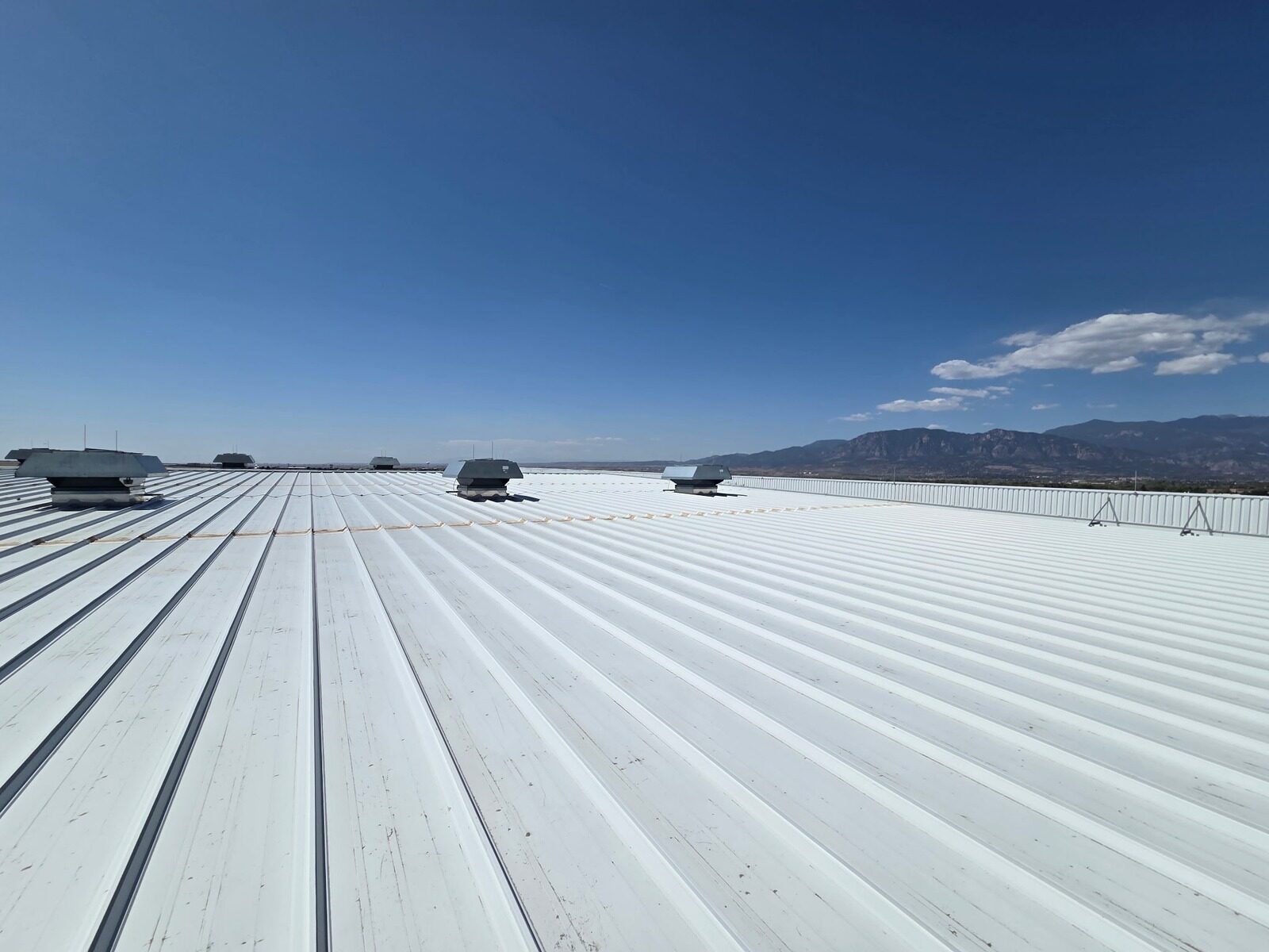 White reflective coating on a standing seam metal roof with Colorado Springs mountain views