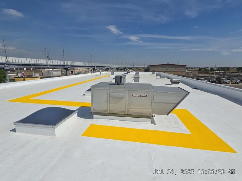 White reflective coating on a commercial flat roof with yellow safety walkway markings