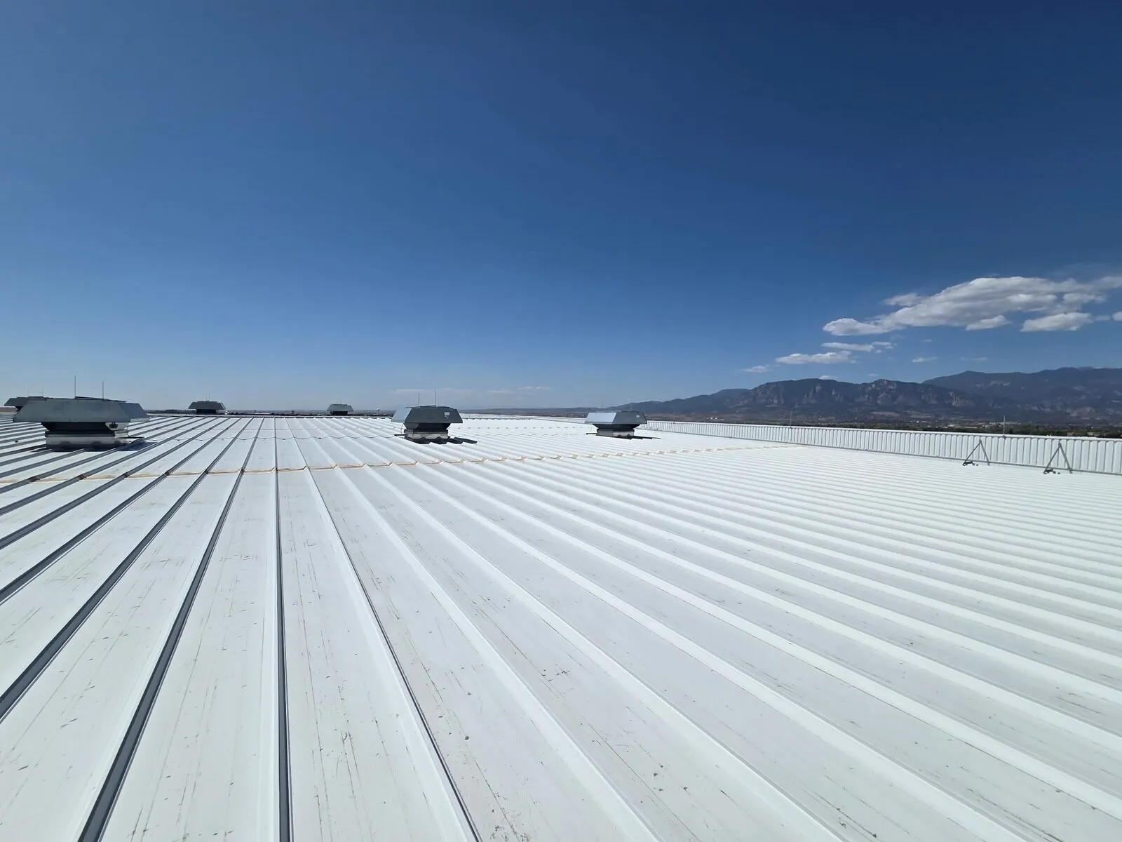 White reflective coating on a standing seam metal roof with Colorado Springs mountain views
